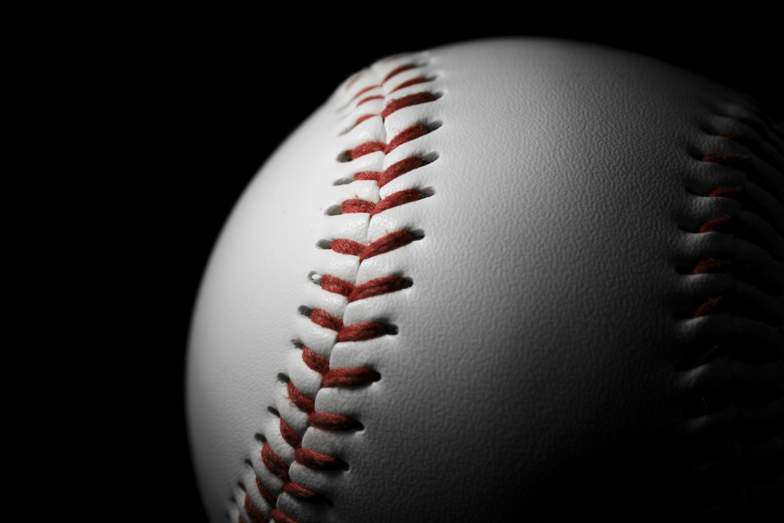 White leather baseball isolated on black with spotlight on it. Sports concept.